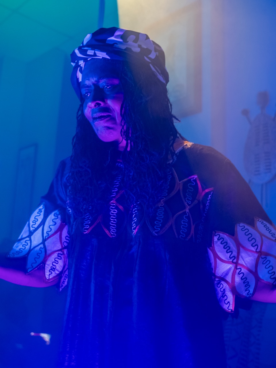 A performer in costume under stage light during the Village Treasures shoot